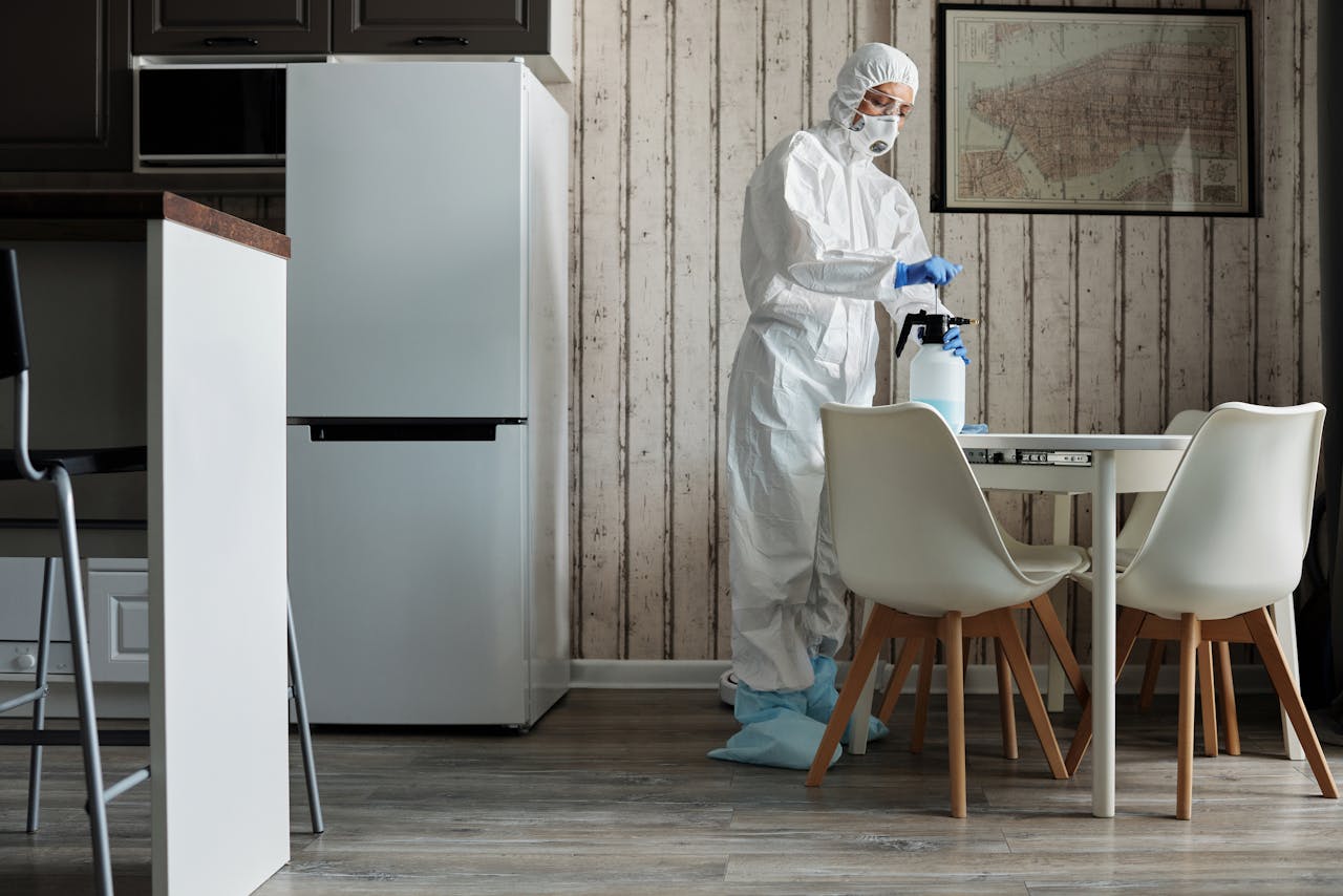 Crafting Captivating Headlines: Your awesome post title goes here Person in hazmat suit disinfecting a modern kitchen table with spray bottle for hygiene.